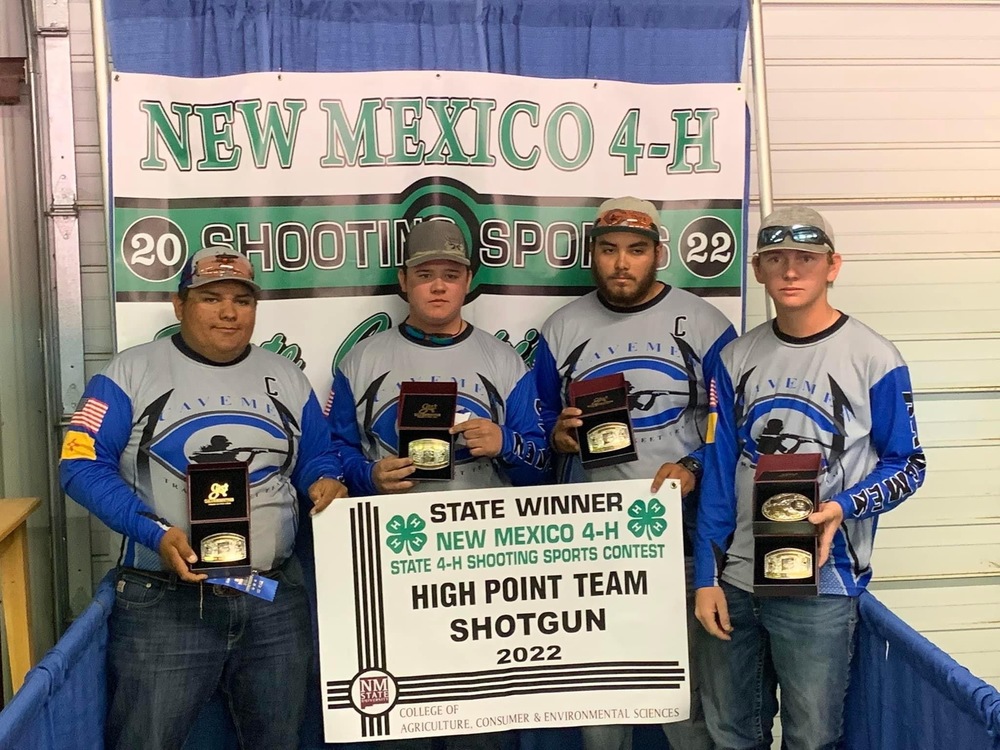 Four students pose with state banner for High Point Team Shotgun