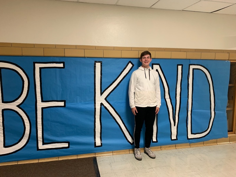 CIS Students stands in front of Be Kind Sign
